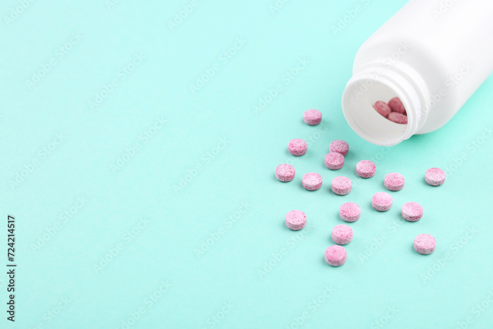 Bottle and vitamin pills on turquoise background, closeup. Space for text Bottle and vitamin pills on turquoise background, closeup. Space for text