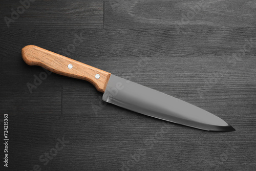 One sharp knife on black wooden table, top view