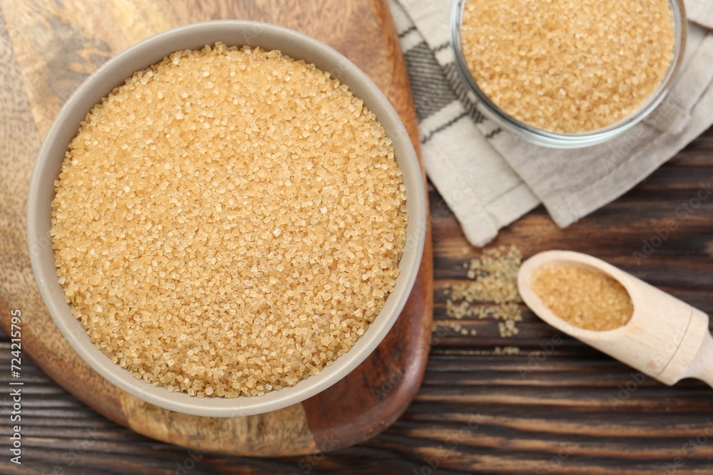 Brown sugar in bowls and scoop on wooden table, flat lay Brown sugar in bowls and scoop on wooden table, flat lay