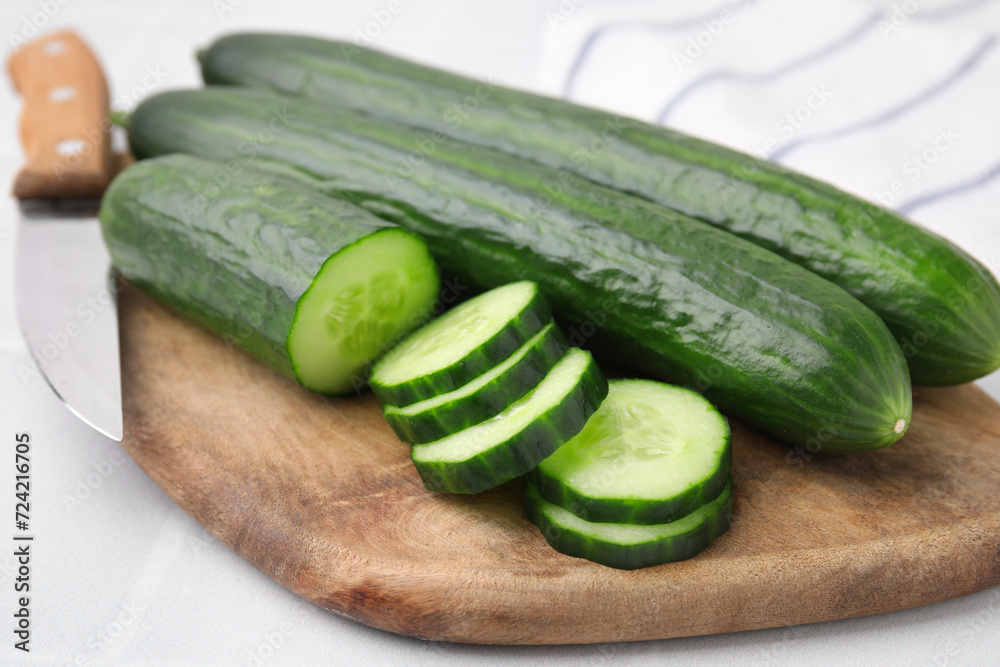 Fresh whole and cut cucumbers on white table, closeup Fresh whole and cut cucumbers on white table, closeup