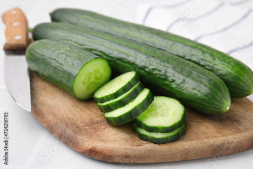 Fresh whole and cut cucumbers on white table, closeup