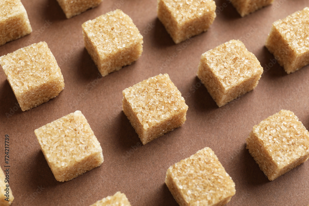 Brown sugar cubes on color background, above view