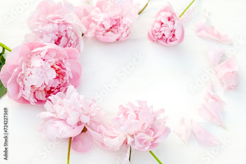 Blossoming peonies in varying shades of pink, thoughtfully arranged on a white table, romance and celebration. Top view.
