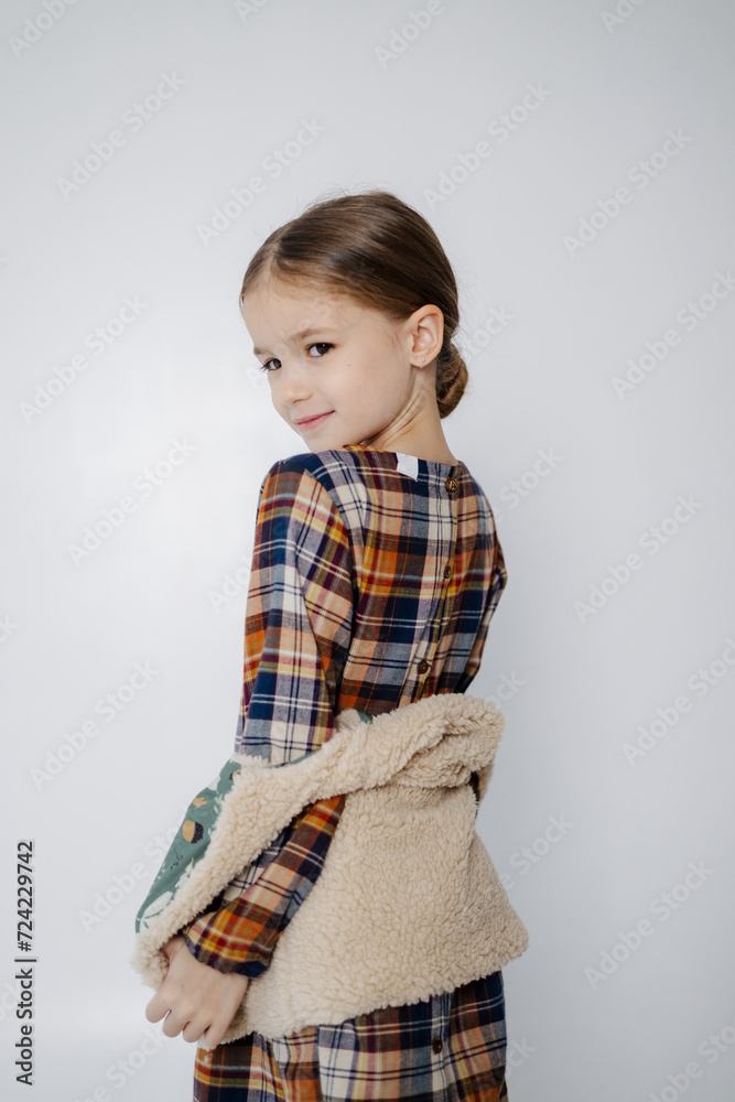 studio portrait of a beautiful girl wearing a checkered dress and a woolen vest