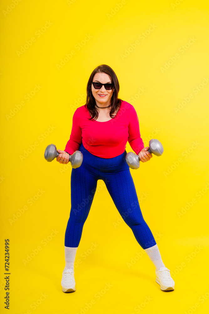 Young smiling happy chubby overweight plus size big fat fit woman warm up training hold dumbbells Young smiling happy chubby overweight plus size big fat fit woman warm up training hold dumbbells