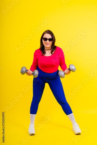Young smiling happy chubby overweight plus size big fat fit woman warm up training hold dumbbells