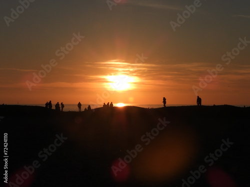 Persone che camminano sulla spiaggia al tramonto 