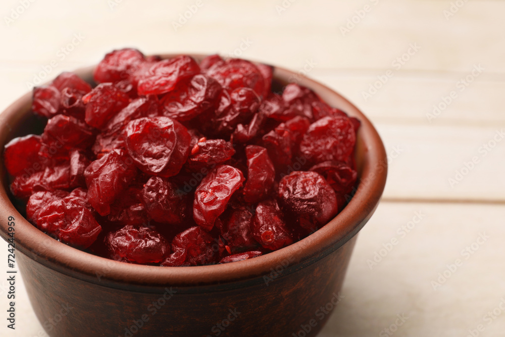 Tasty dried cranberries in bowl on light wooden table, closeup Tasty dried cranberries in bowl on light wooden table, closeup