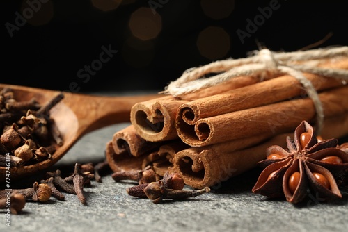 Different spices on gray table against black background, closeup