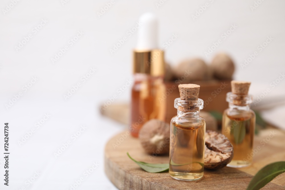 Nutmeg essential oil and nuts on white table. Space for text Nutmeg essential oil and nuts on white table. Space for text