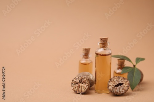 Nutmeg essential oil and nuts on beige background. Space for text