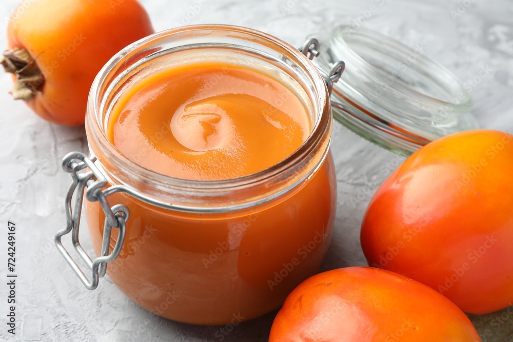 Delicious persimmon jam and fresh fruits on grey table, closeup Delicious persimmon jam and fresh fruits on grey table, closeup