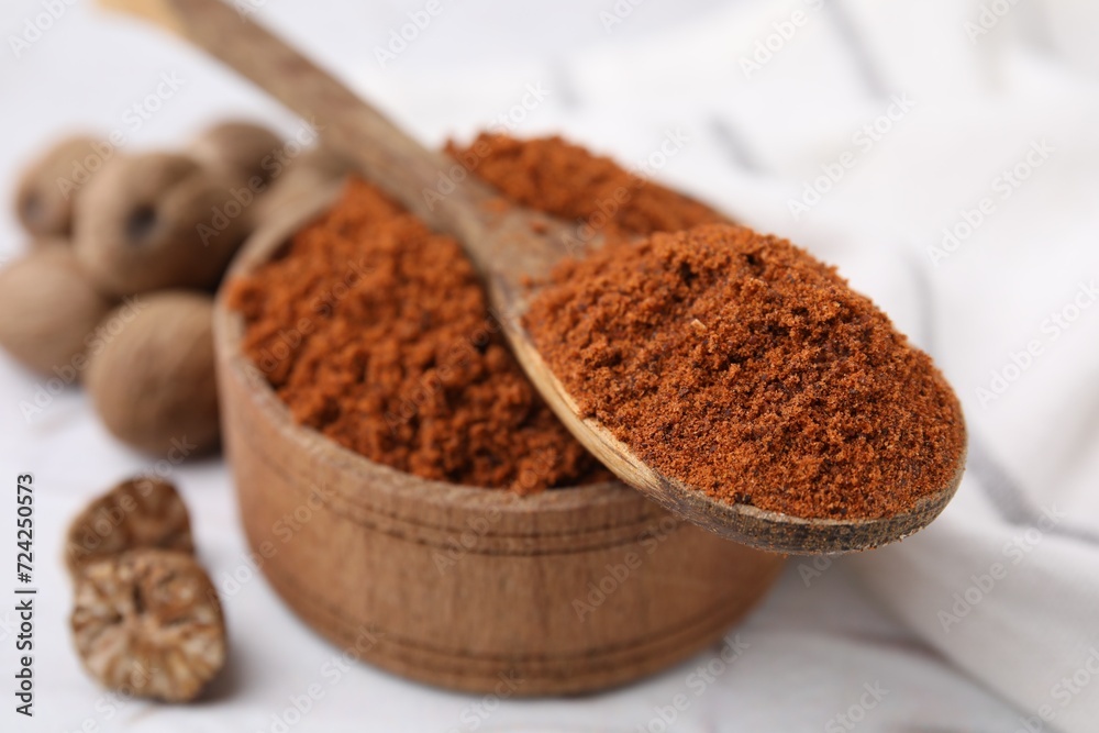 Bowl and spoon with nutmeg powder on white table, closeup Bowl and spoon with nutmeg powder on white table, closeup