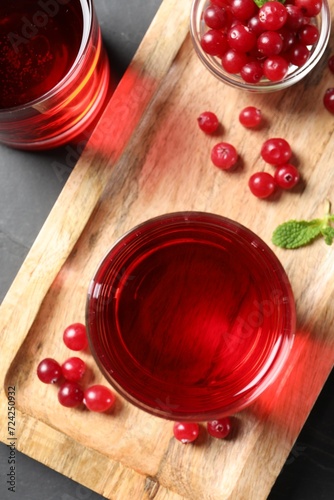 Tasty refreshing cranberry juice and fresh berries on grey table, top view