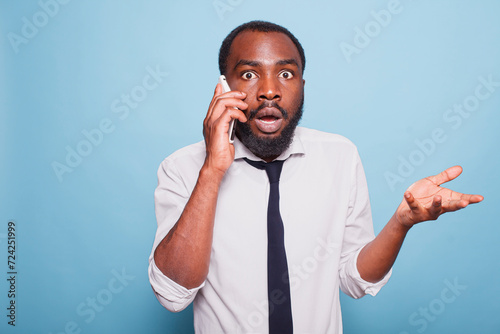Shocked businessman looking surprised with open mouth hearing unbelievable situation on mobile device. Amazed person with big eyes jaw dropping having a phone call. Astonished office worker.