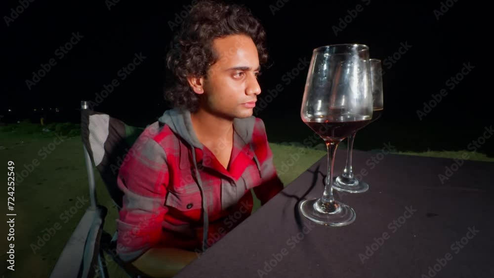 thoughtful Man sitting at a table at night with a large wine glass thinking unhappy upset expression and dramatic lighting thoughtful Man sitting at a table at night with a large wine glass thinking unhappy upset expression and dramatic lighting