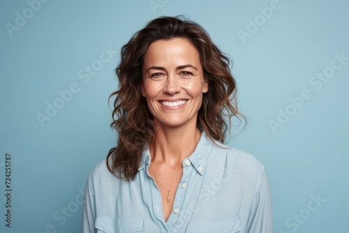 Portrait of a smiling middle aged woman looking at the camera over blue background