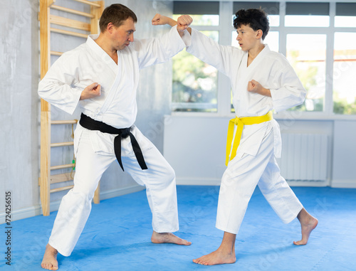 Karate lesson for teenager - guy and trainer are sparring in the gym