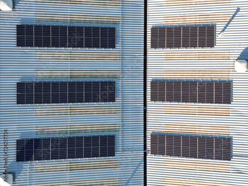 Aerial top down view of solar panel photovoltaic cells on roof of factory, UK