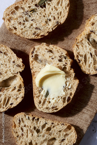 Artisan bread slices with butter on wooden board photo