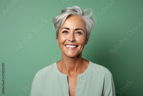 Portrait of a happy senior woman smiling at camera against green background