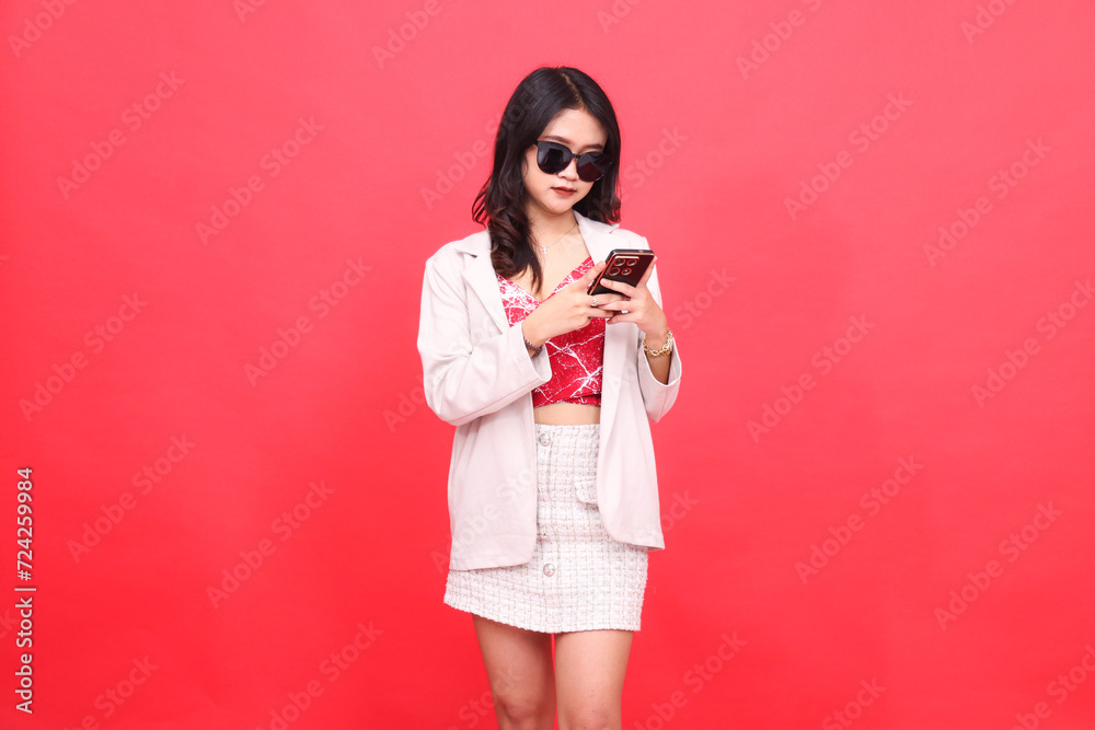 A beautiful Asian Indonesian woman wearing glasses operates a telephone wearing a cream-colored blazer A beautiful Asian Indonesian woman wearing glasses operates a telephone wearing a cream-colored blazer