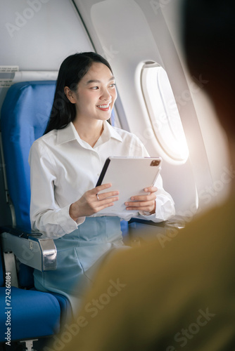 Female asian woman holding Tablet while sitting in airplane.