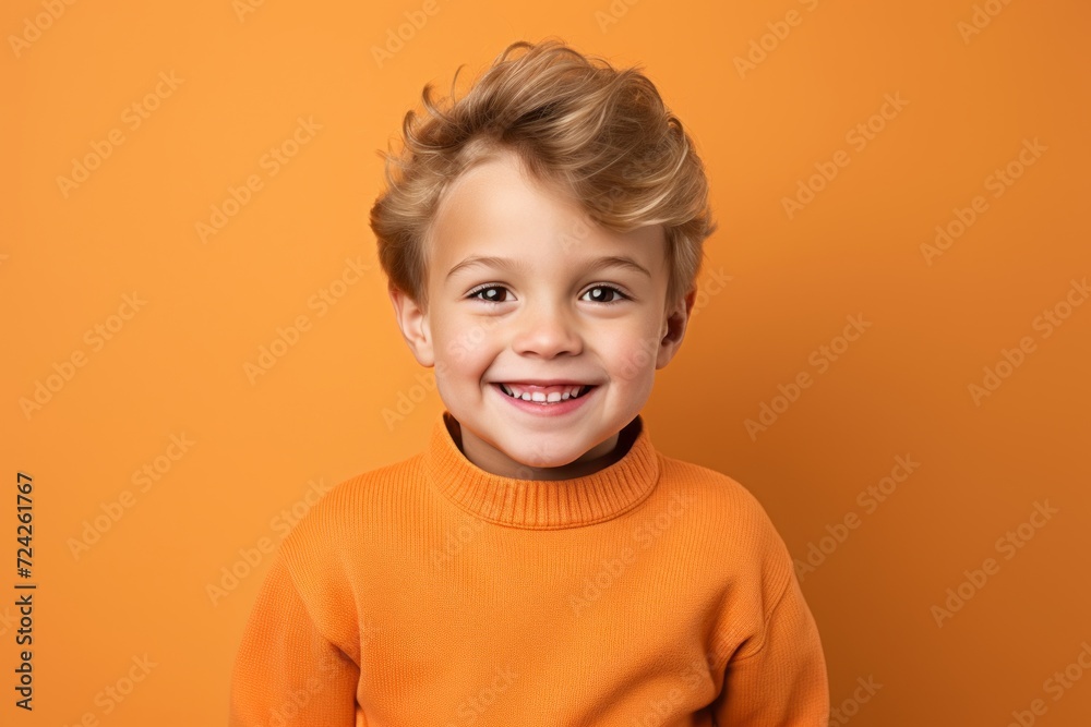 Portrait of a smiling little boy in orange sweater on orange background Portrait of a smiling little boy in orange sweater on orange background