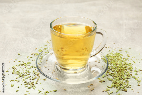 Aromatic fennel tea in cup and seeds on light grey table, closeup