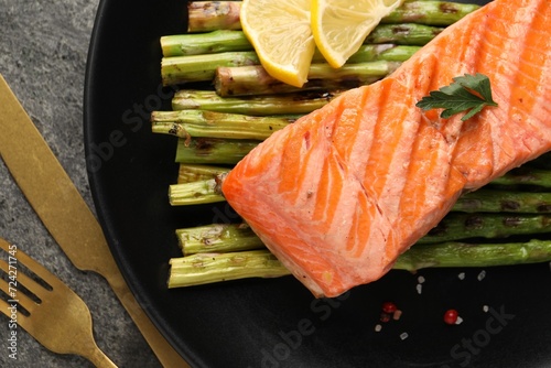 Tasty grilled salmon with asparagus, lemon and spices served on table, flat lay
