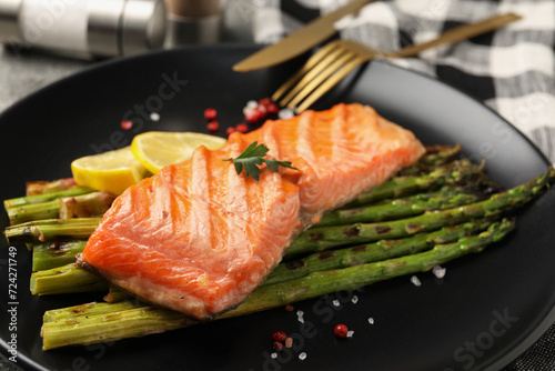 Tasty grilled salmon with asparagus and spices served on table, closeup