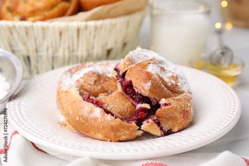 Delicious bun with sugar powder and berries on white table, closeup Delicious bun with sugar powder and berries on white table, closeup