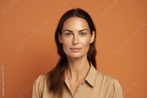 Portrait of a beautiful young woman looking at camera and smiling while standing against orange background