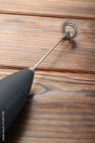 Black milk frother wand on wooden table, closeup