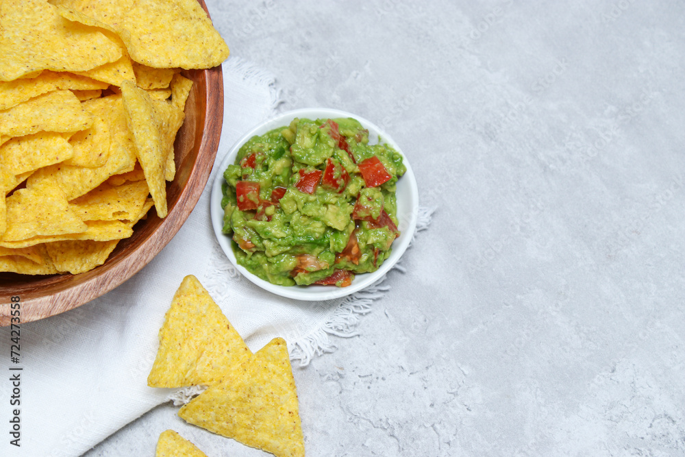 Close up of tortilla in a wooden bowl and fresh guacamole dip on grey marble table Close up of tortilla in a wooden bowl and fresh guacamole dip on grey marble table
