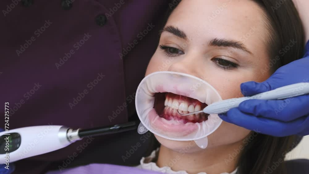 Dentist in gloves places temporary dental filling with tool on woman ...