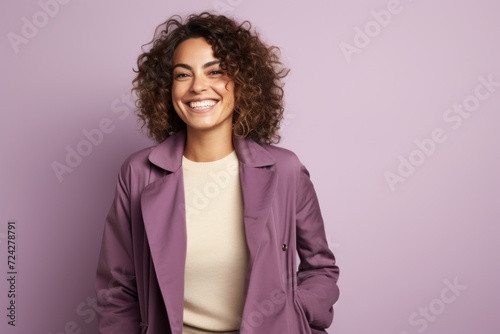 Smiling young woman with curly hair in a stylish jacket on a purple background