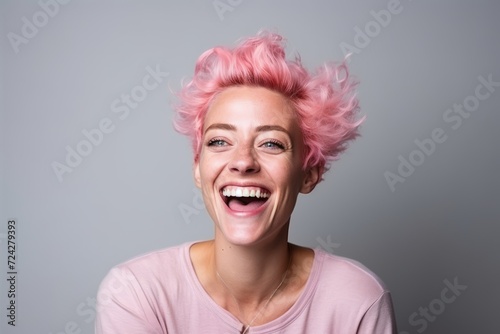 Portrait of a happy young woman with pink hair against grey background