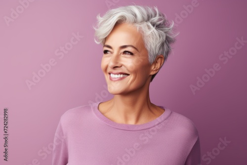 Beautiful mature woman with short grey hair. Studio shot over purple background.