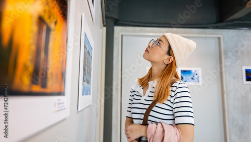 Fotografi Woman standing she looking art gallery collection in front framed paintings pict