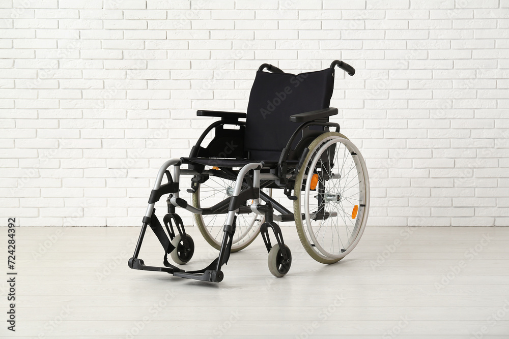 Empty wheelchair near white brick wall Empty wheelchair near white brick wall