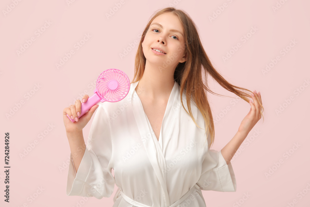 Beautiful young woman with handheld mini fan on pink background Beautiful young woman with handheld mini fan on pink background