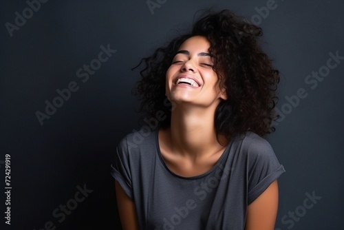 Portrait of a beautiful young latin woman laughing on dark background