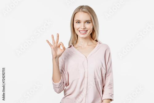 Young blonde woman in casual showing OK gesture and looking at camera isolated on white background. Positive emotion of confirmation accepted approved concept