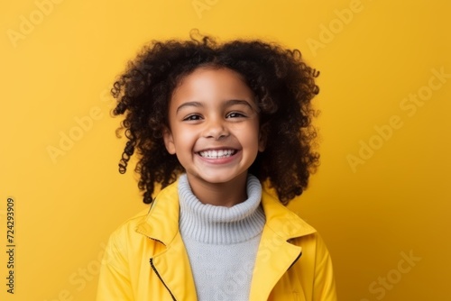 Portrait of smiling african american little girl in yellow jacket on yellow background