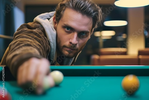 A skilled pool player takes aim with determination, his focused expression mirrored in the gleaming pool ball held tightly in his hand as he prepares to sink it into the corner pocket of the vibrant  photo