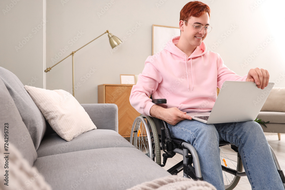 Young man in wheelchair with laptop at home