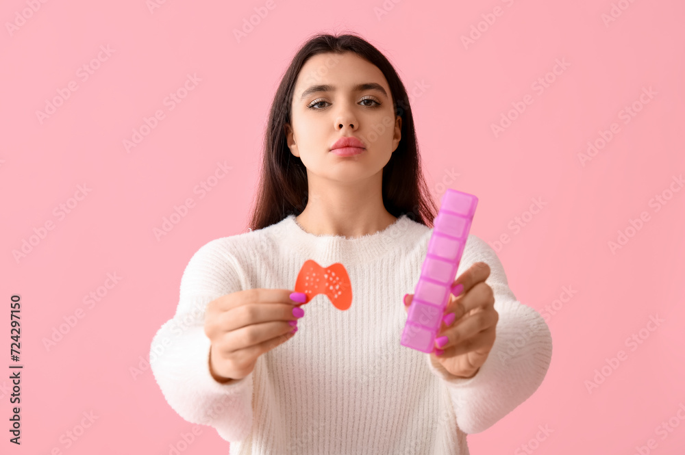 Young woman with paper thyroid gland and pill box on pink background Young woman with paper thyroid gland and pill box on pink background