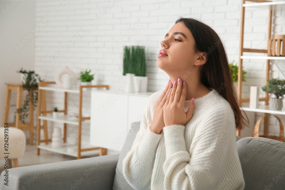 Young woman with thyroid gland problem sitting on sofa at home Young woman with thyroid gland problem sitting on sofa at home