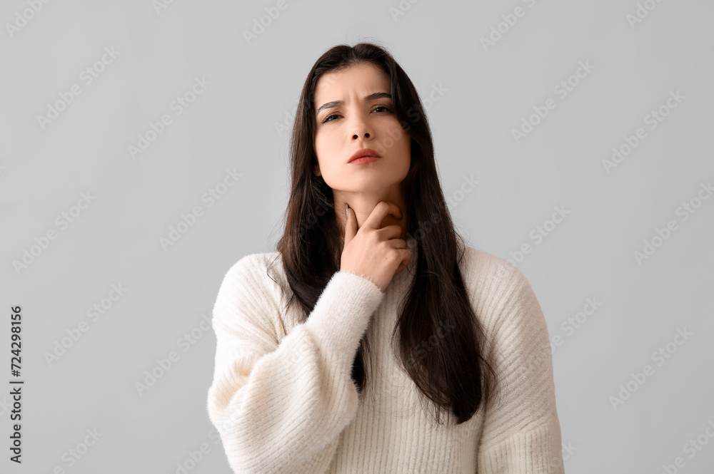 Young woman with thyroid gland problem on grey background Young woman with thyroid gland problem on grey background